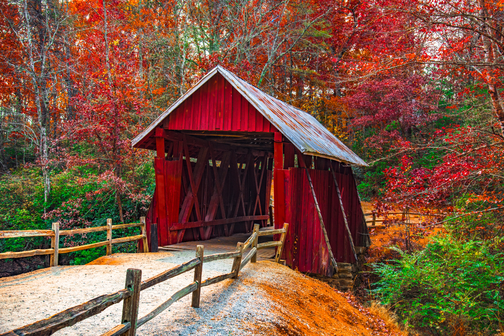 Photo of the bright red Campbells Covered Bridge surrounded by vibrant fall foliage.