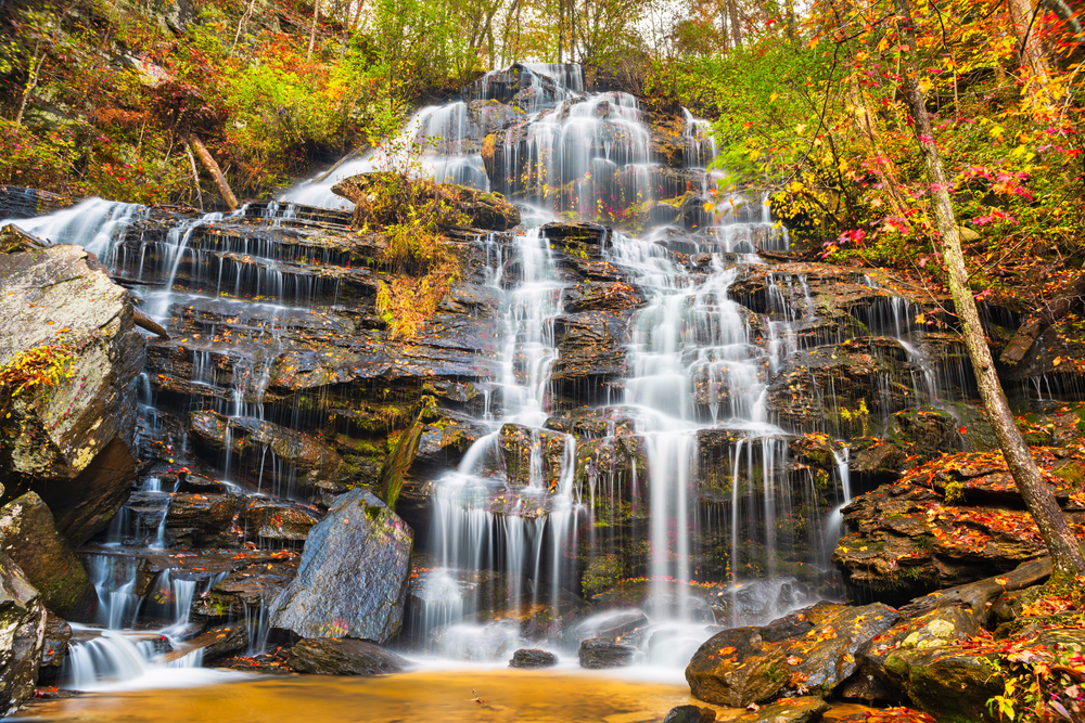  Issaqueena Falls cascading down rocks and surrounded by fall foliage.