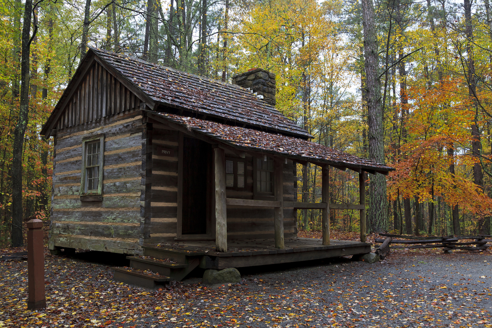  log cabin surrounded by foiliage-covered woodlands at the living history farm at Kings Mountain, South Carolina.