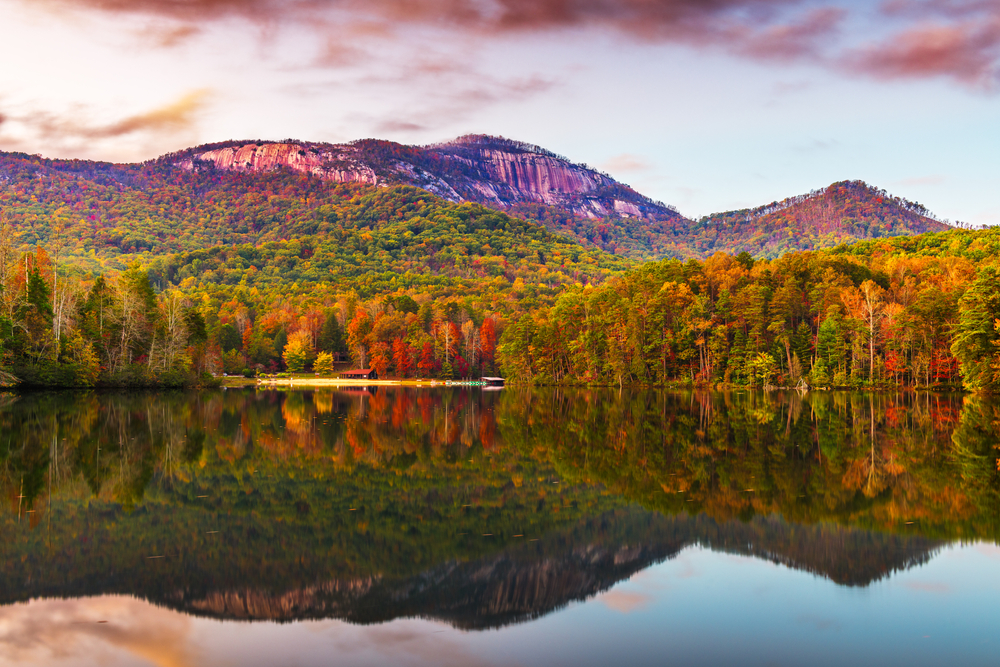  fall colored trees reflecting on the water of Lake Oolenoy with Table Rock Mountain in the background at sunset with a pink sky