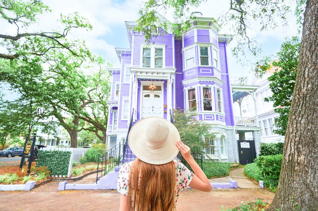 Woman in Savannah georgia standing for an Instagram photo in front of a purple house