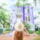 woman holding her hat in front of purple house in Savannah georiga