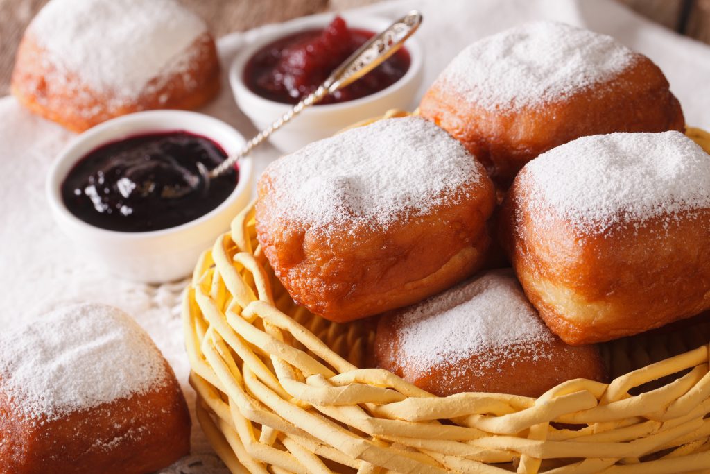 A basket of Beignets on a table with some jam