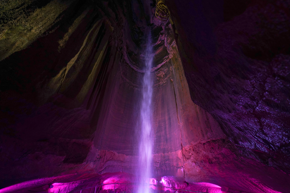 Photo of Ruby Falls  inside of an underground cavern illuminated by colorful lighting