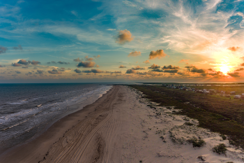 ariel photo of a sandy beach and houses to the side