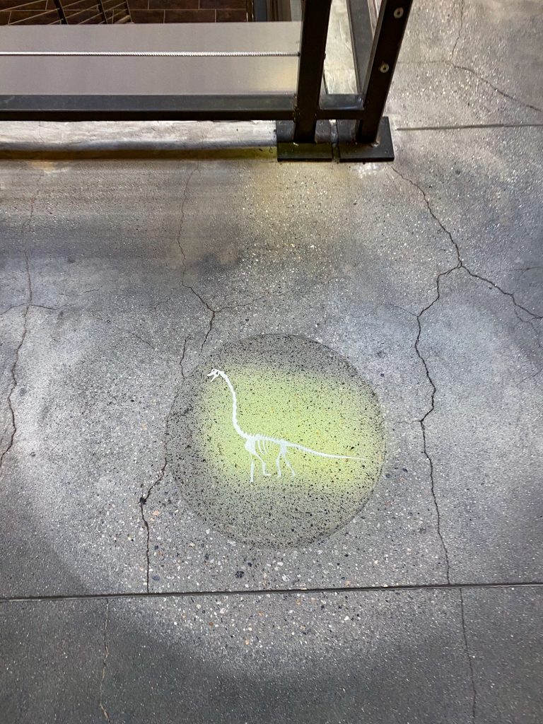A sidewalk symbol indicates the closeby entrance to the Ultimate Dinosaur adventure in the Plant Riverside District.