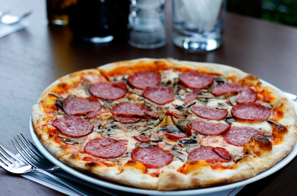 A pepperoni and mushroom pizza on a plate at the table