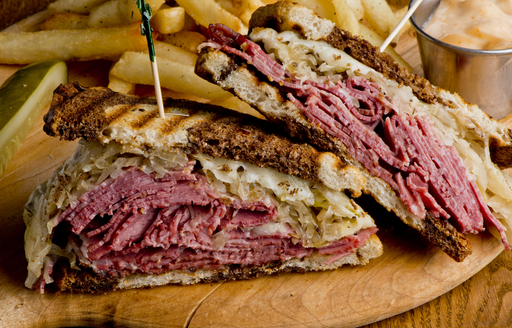 A Rueben Sandwich with sauerkraut and mustard with French fries