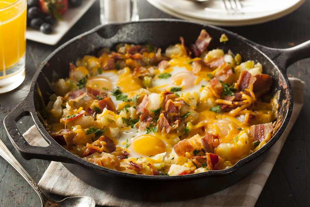 a breakfast skillet with eggs, bacon, potatoes, cheese and herbs served with glass of OJ and fruit at this breakfast restaurants in Gatlinburg