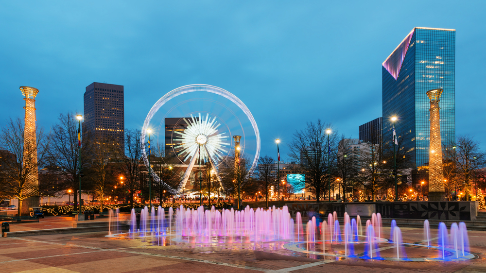 Centennial Olympic Park with the water fountains and Sky View Ferris Wheel with the backdrop of downtown Atlanta at nighttime.