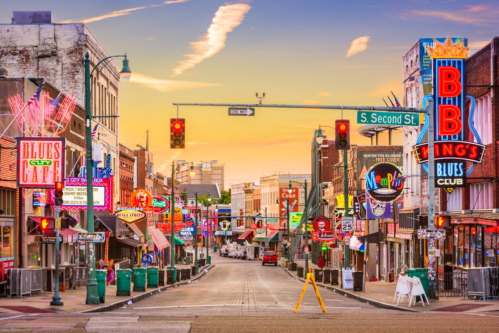 A photo of a street full of neon signs promoting restraunts, blues clubs, and more along Beale Street in Memphis Tennessee.