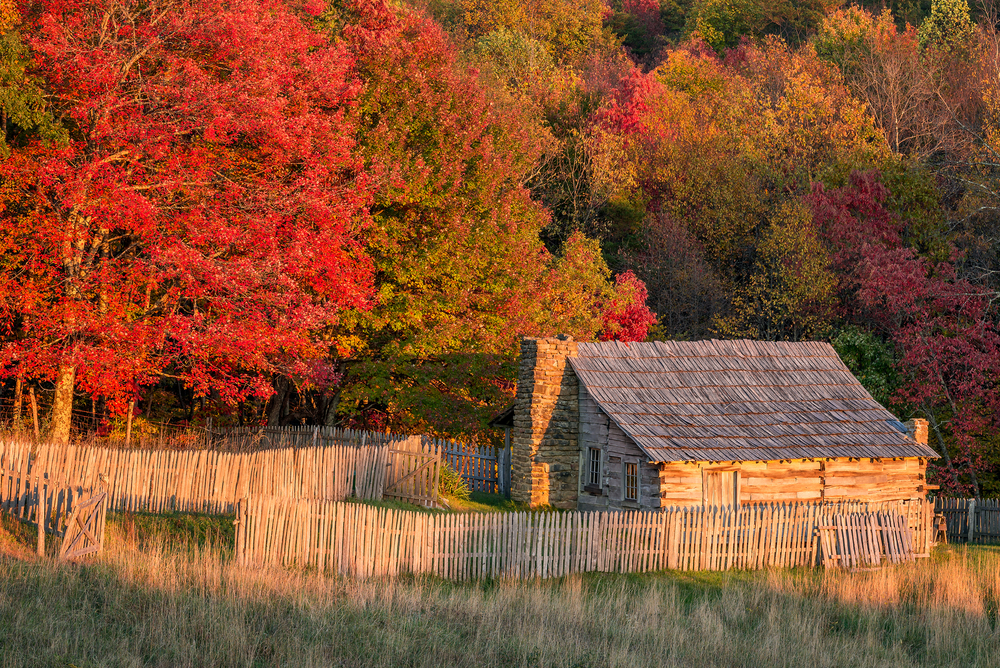 View of autumn leaves in red, gold, and purple, overlooking a rustic cabin in Cumberland Gap National Park, one of the best things to do in Kentucky.