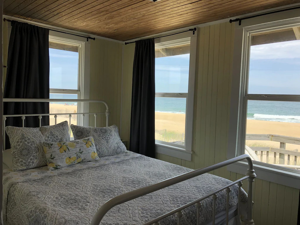 Photo of a bedroom with panoramic ocean view inside Lemonade Cottage, one of the cutest Outer Banks vacation rentals.