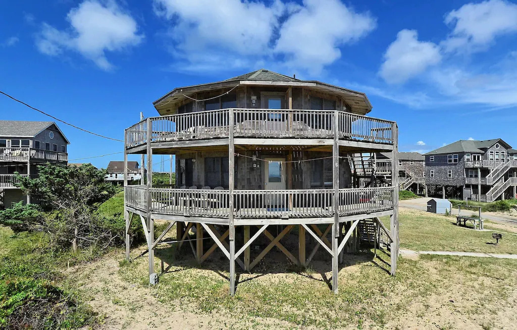 Photo of the exterior of Point Break Cottage, a two story circular-shaped round cottage with  wrap around decks shaker siding.
