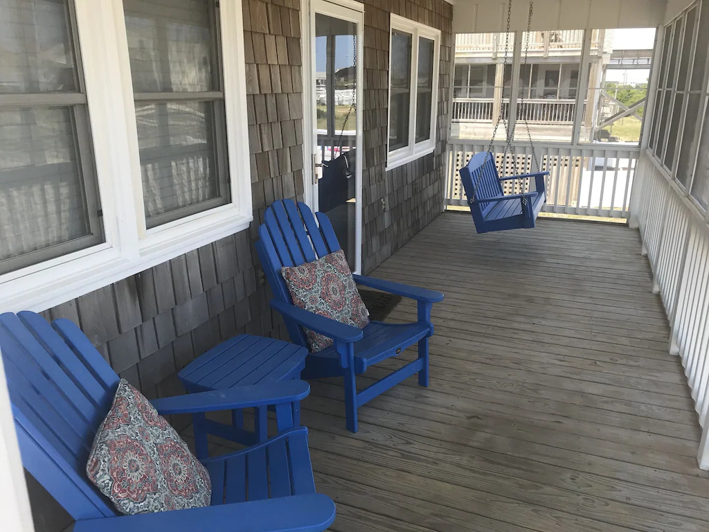 Photo of blue Adirondack chairs and porch swing on the porch at  Sandy toes, one of the best Outer Banks vacation rentals!
