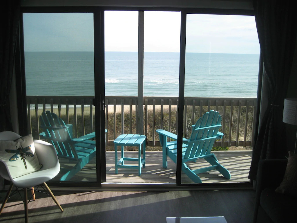 Photo of turquoise Adirondack chairs overlooking the ocean on the balcony of Wave-Hi.