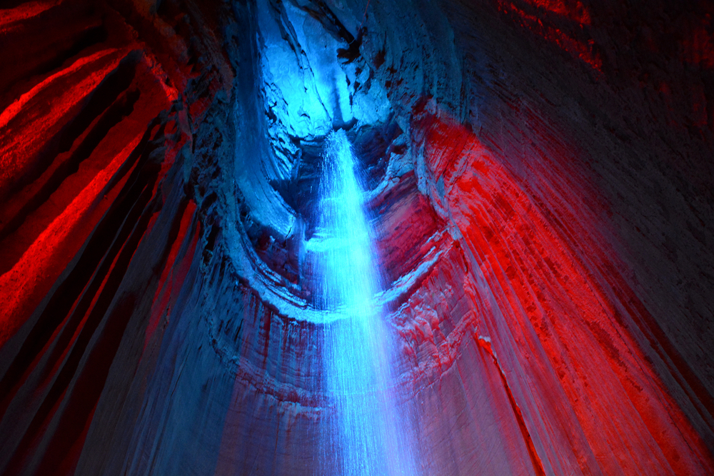 A picture of Ruby Falls waterfall cascading inside a cave that is lit up with blue and red lights.