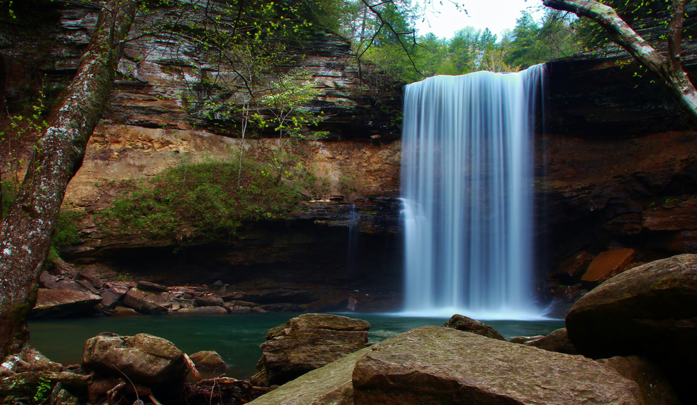 A photo of Greeter Falls flowing over the walls of rocks into a calm pool of water located in South Cumberland State Park.