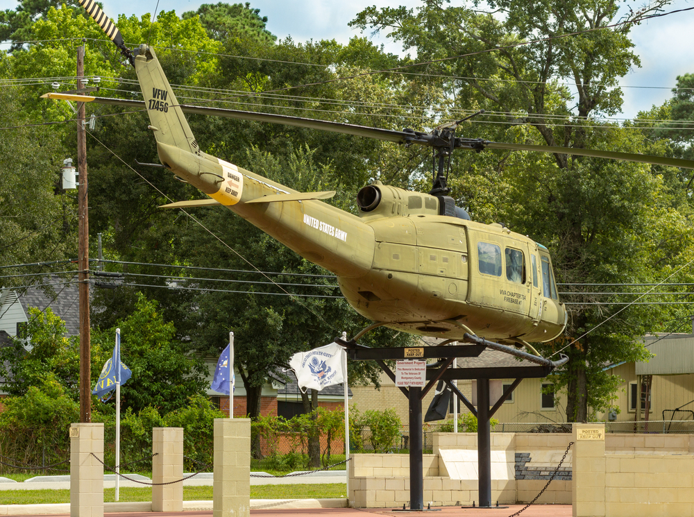 A military helicopter is displayed behind several military flags on the VFW Hall in Conroe, Texas.