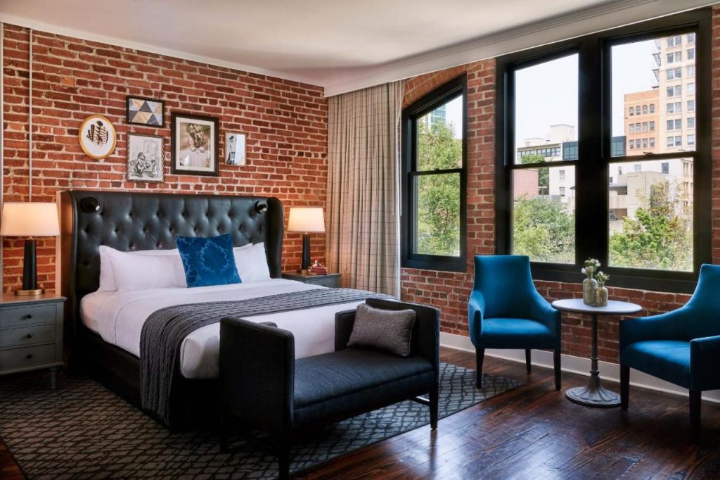 Photo of a room in The Foundry Hotel, featuring exposed brick walls and modern furniture. An excellent choice when choosing where to stay in Asheville