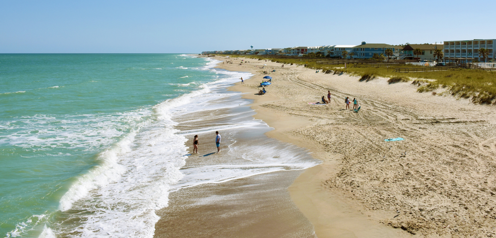 pretty blue ocean and sandy beach with a line of hotels on the coast