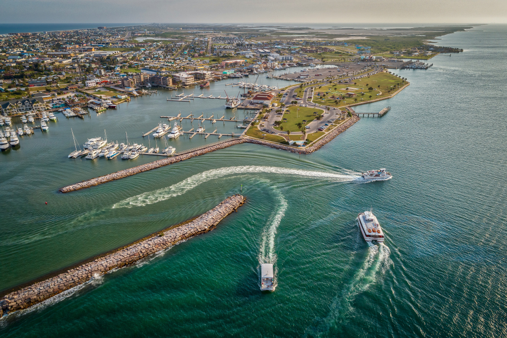 aerial photo of bay and ocean with boats driving through the water