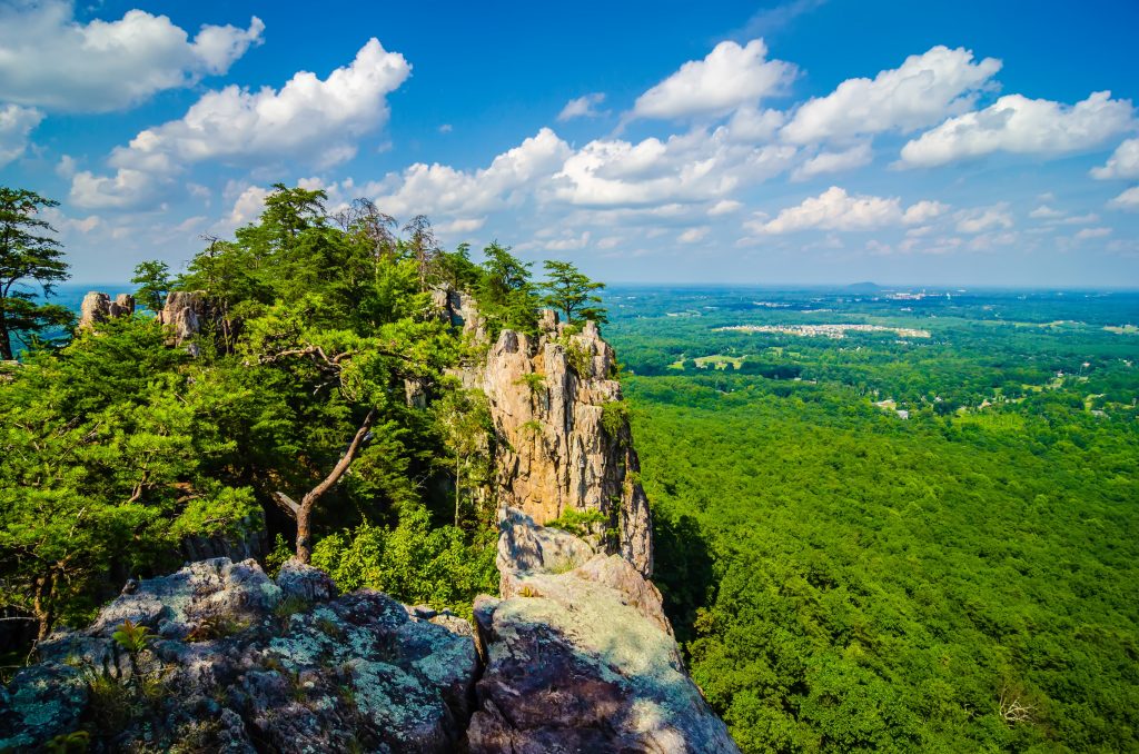 The peak of Crowders Mountain, one of the best things to do in North Carolina, casts a shadow on the lush forest below.