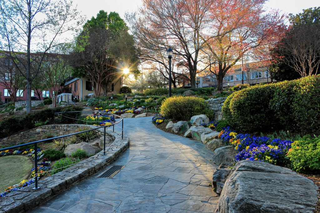 A stone pathway lined with rocks and beautiful flowers winds through Falls Park, one of the best things to do in North Carolina