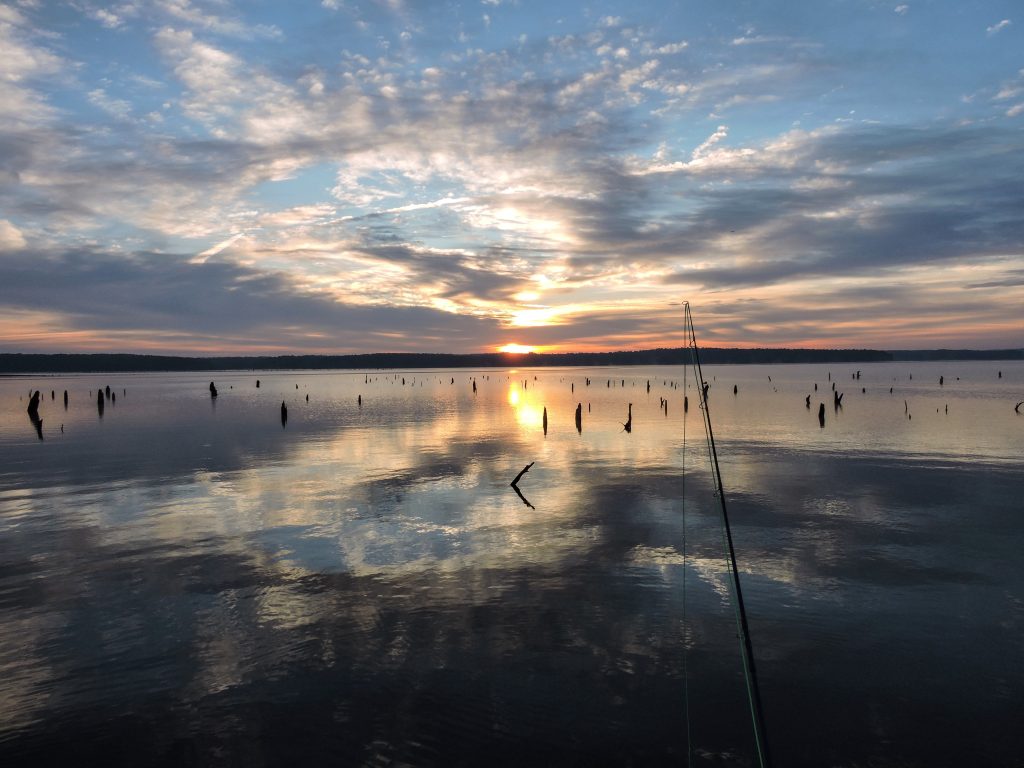 A fishing line is cast over Jordan Lake as the sun sets over the water.