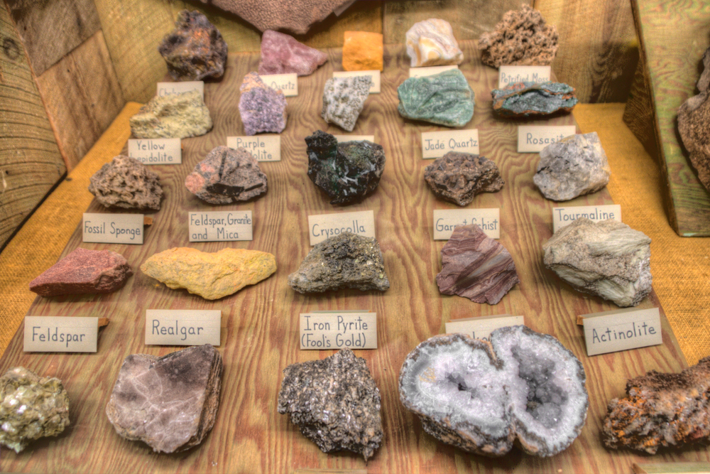 A collection of minerals with small signs in front of them that say what type of mineral they are. They are lined up on a wooden board.