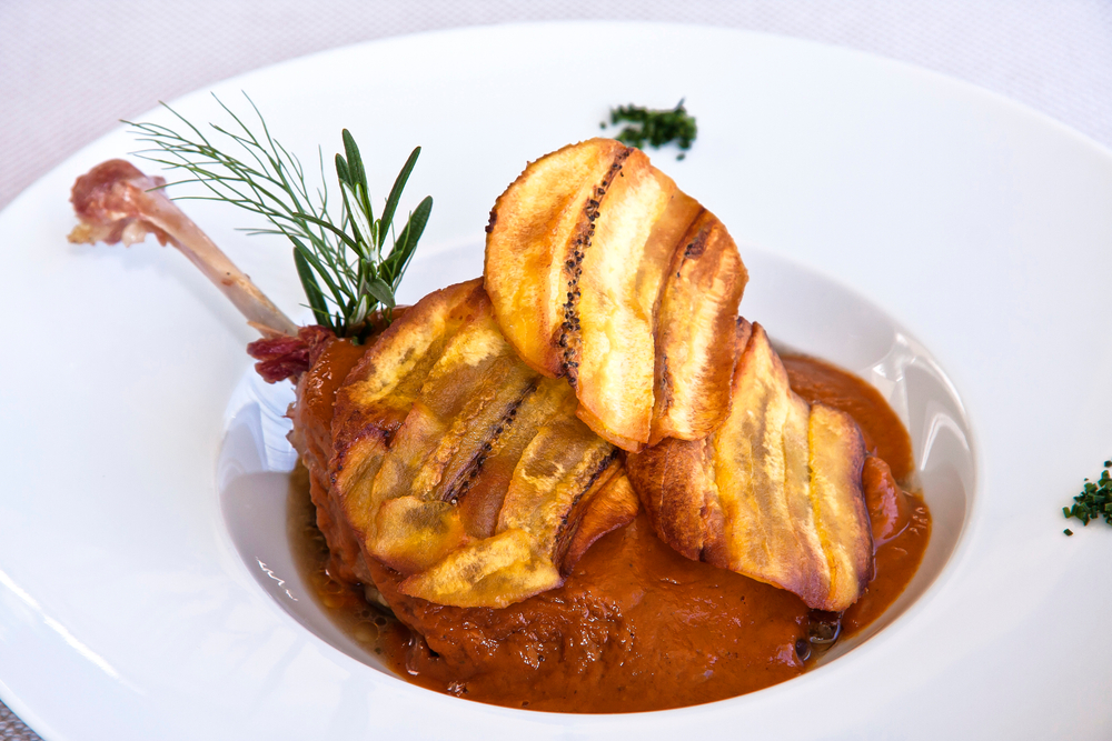 A upscale dish of Mexican pork with roasted plantains served in a red pepper glaze