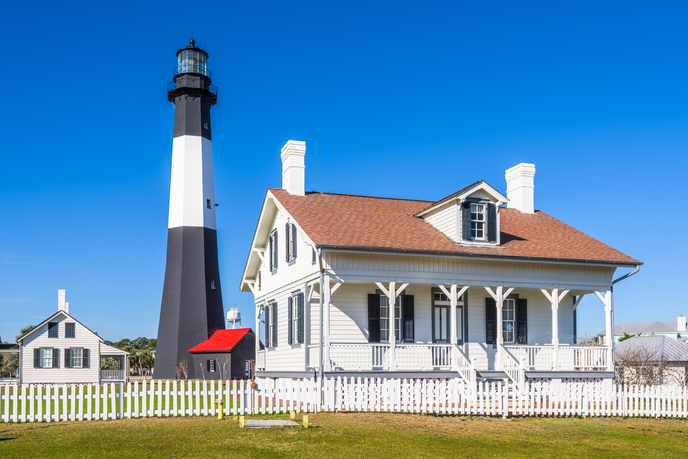 small white building next to a small black and white lighthouse