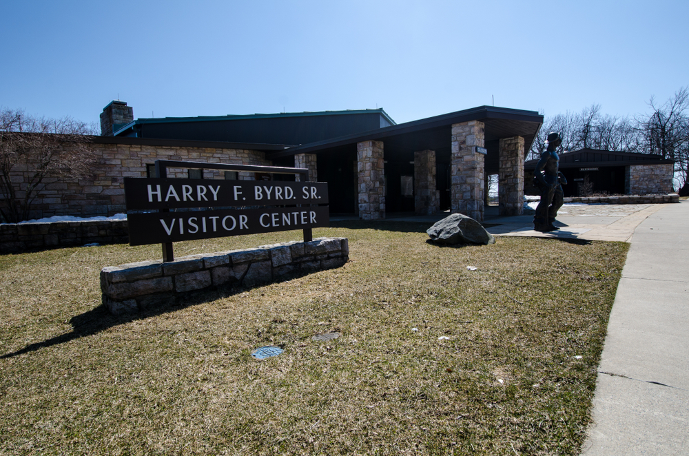 A picture of the sign for Harry F. Byrd. Visitor Center in front of the brick building and statue.
