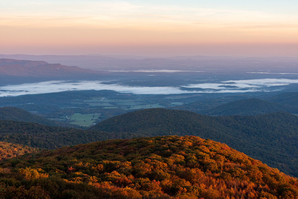 A picture of the view of the foggy valleys at sunrise from an overlook on Hogback Mountain. 