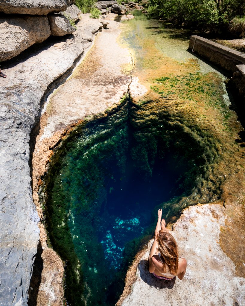 woman sitting in front of Jacob's Well spring in texas