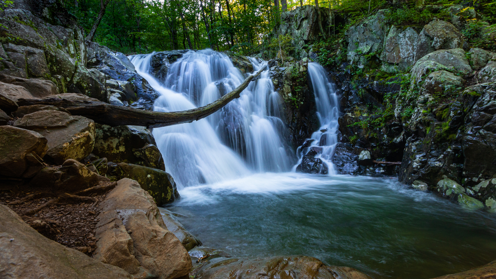 A phot of Rose Water Falls flowing into a pool of water surrounded by rocky walls.