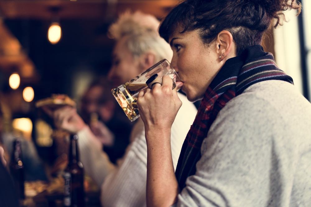 A women drinking a pink of beer in a pub