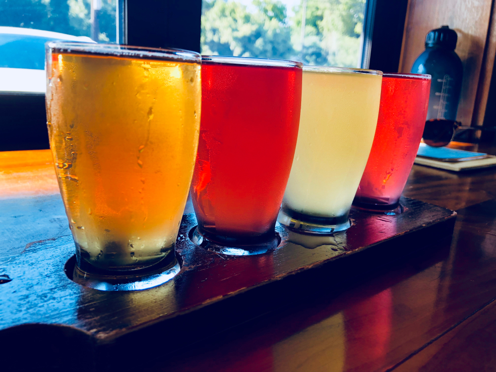 Four pints of beer on a bar in an article about breweries in Asheville