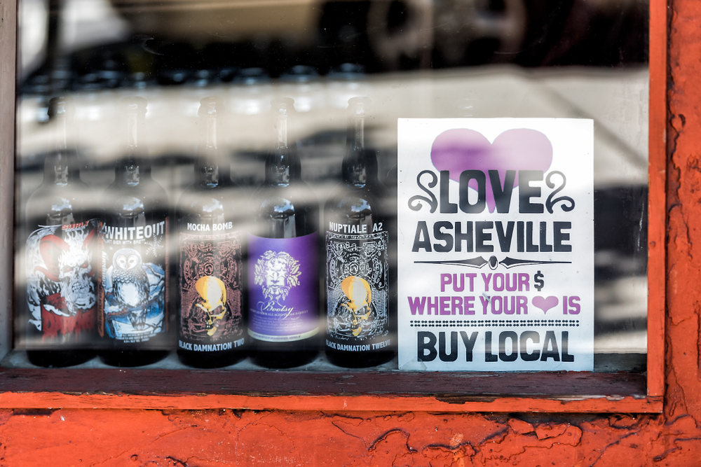 A poster and beers in a window of a brewery in Asheville