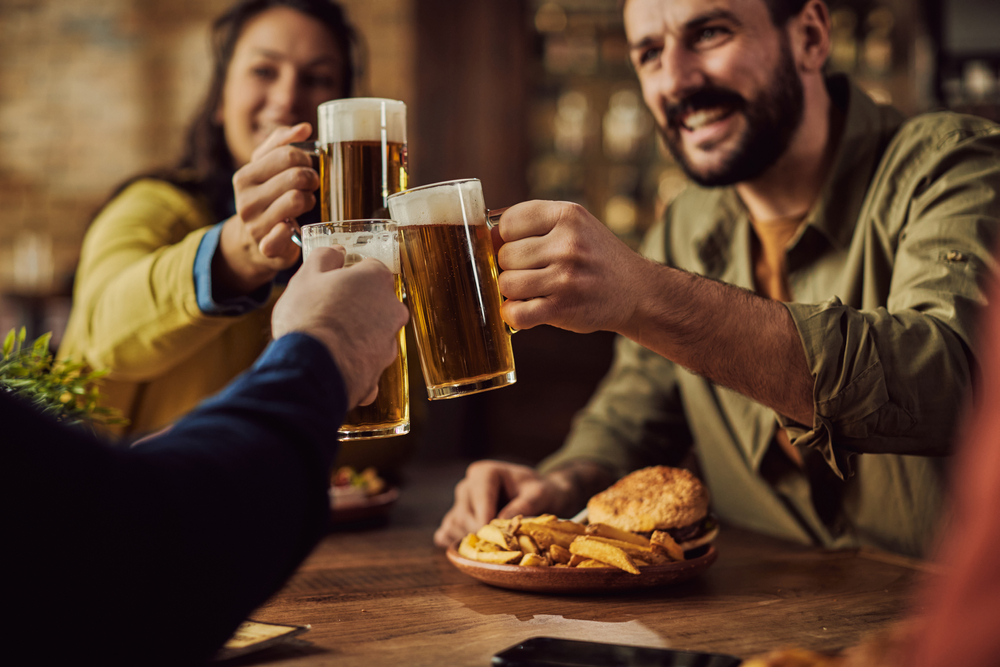 Three people drinking beer and eating in a pub