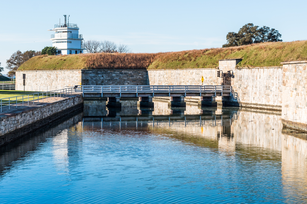 A glassy water filled moat with a bridge across it at Fort Monroe.