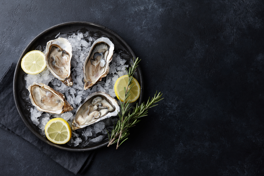 photo of oysters on a half shell with lemon, on a bed of ice 