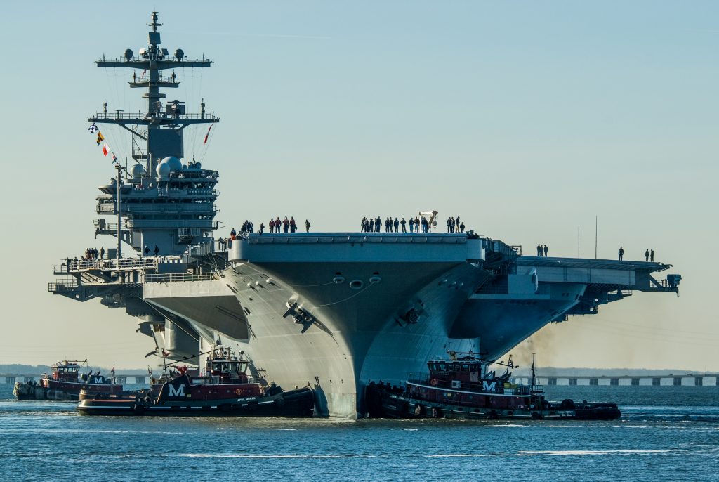 Active duty navy members line a ship in the shipyard