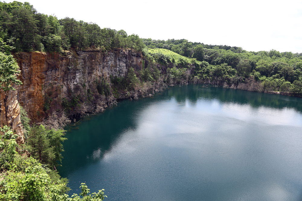 blue body of water surrounded by rock facings and trees