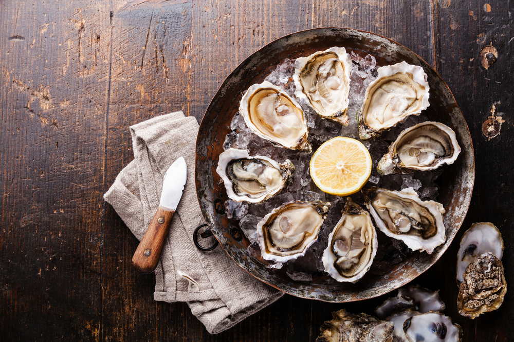 Aerial view of raw oysters served on ice with lemon.