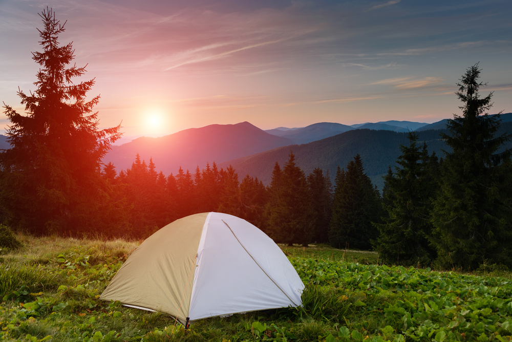 White tent overlooking trees and the Smoky Mountains at sunset