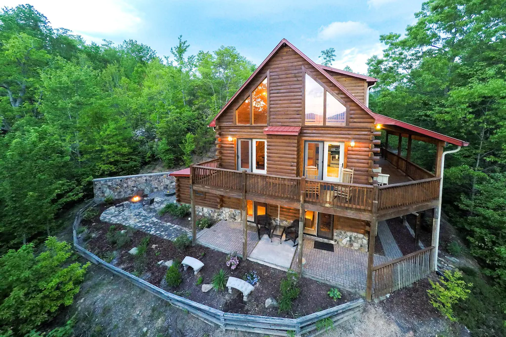 Aerial view of a big, log cabin surrounded by trees.