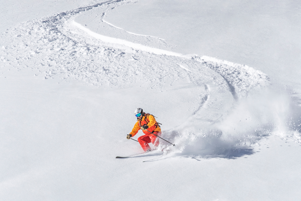 A skier headed down a snowy slope.