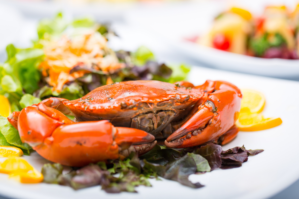 A whole crab on a bed of lettuce.