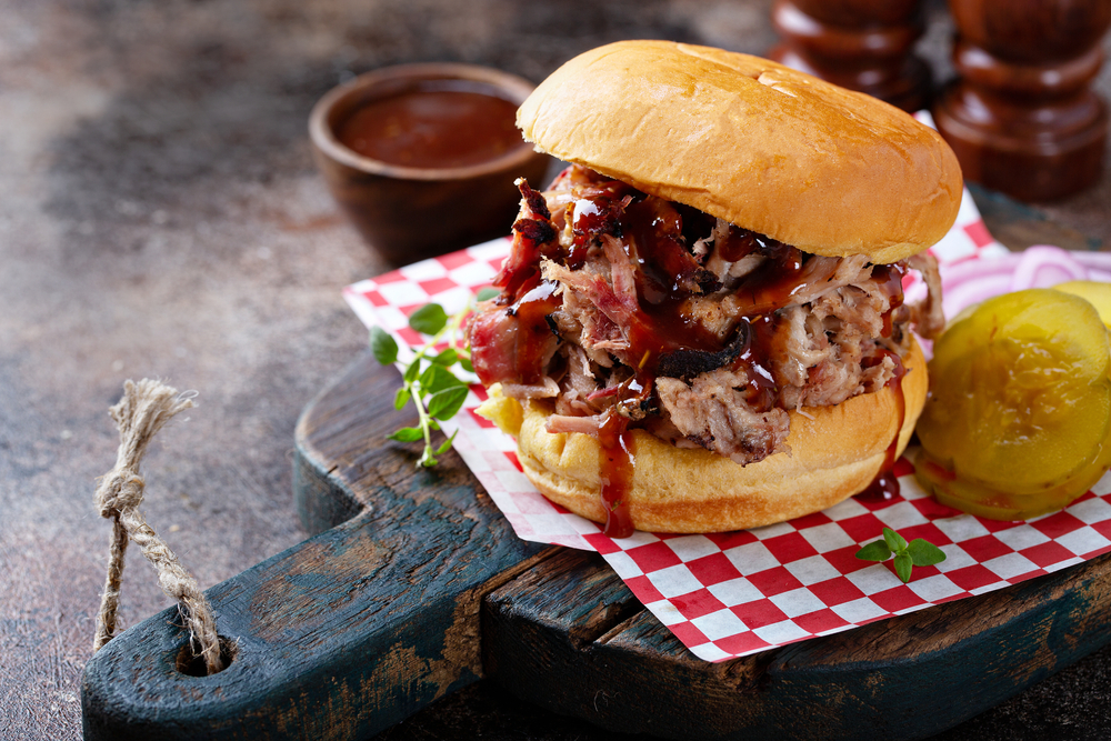 BBQ sandwich served with pickles, representing The Pot Smoker, one of the best restaurants in Augusta GA.